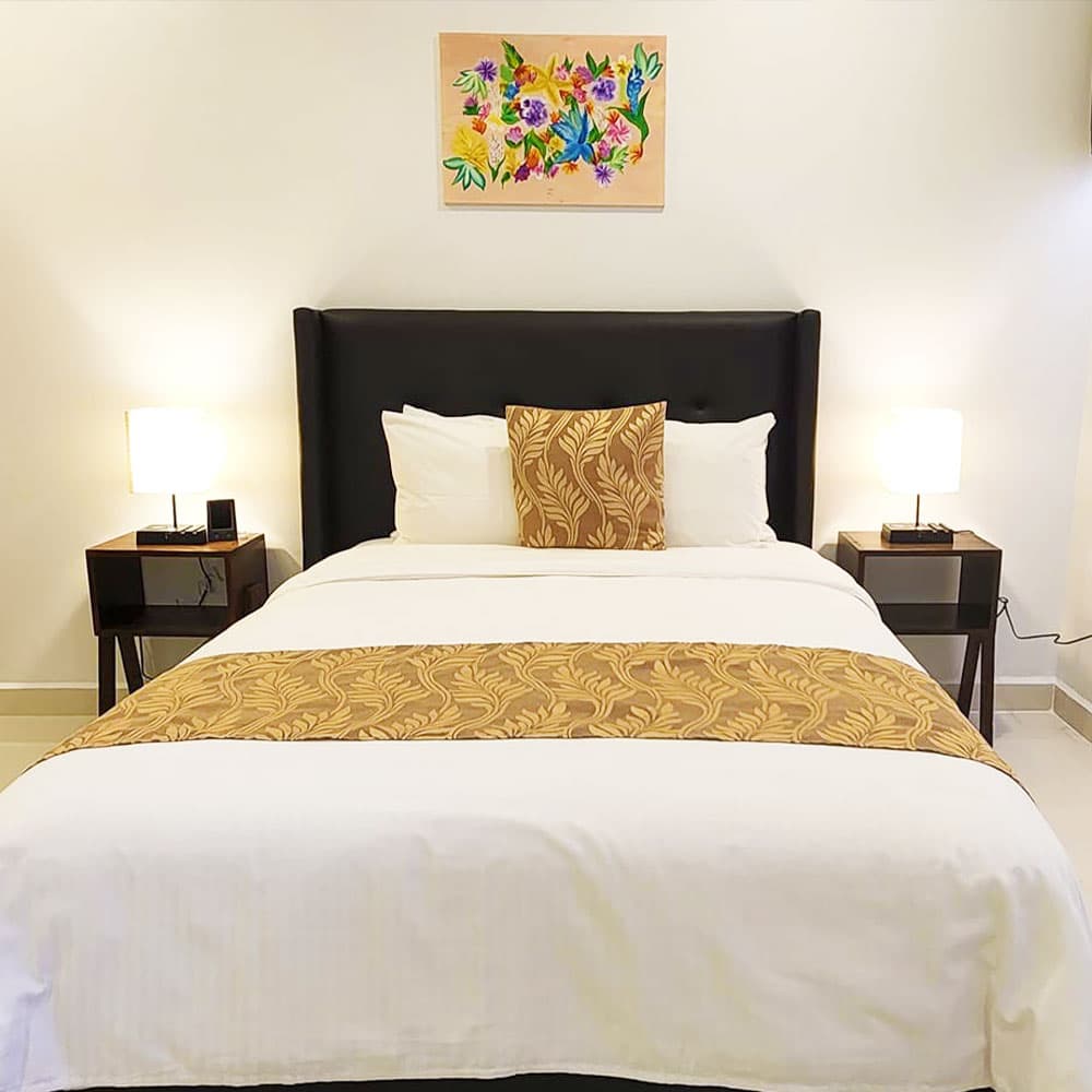 A neatly made bed with decorative pillows and bedside lamps in a cozy room.