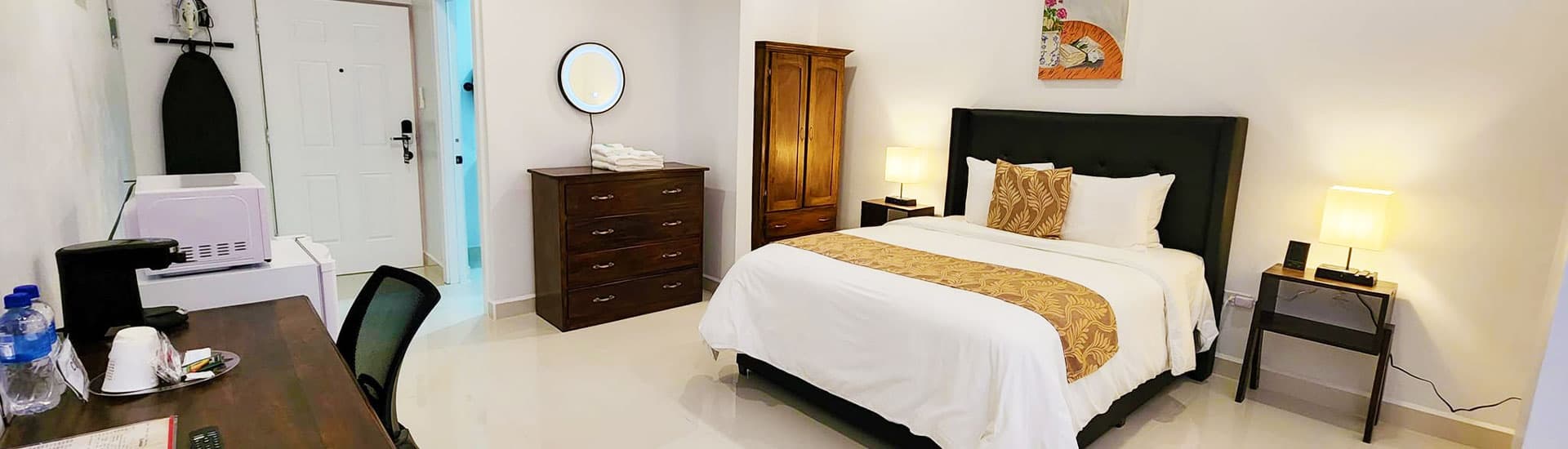A cozy hotel room featuring a neatly made bed, wooden furniture, and soft lighting.